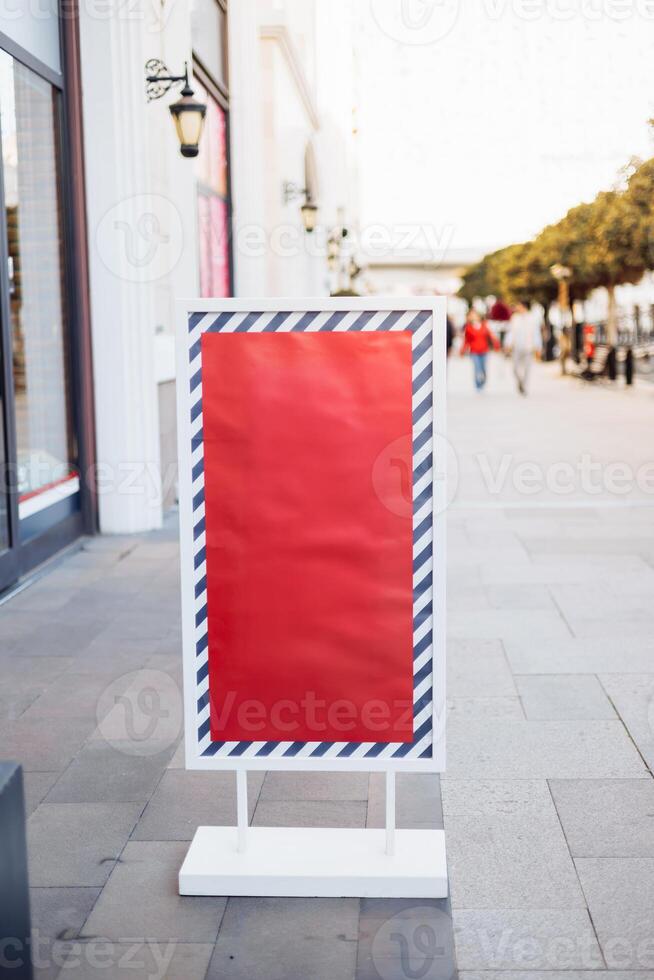 Signboard stands outside shop on a busy street during the afternoon in a shopping district photo