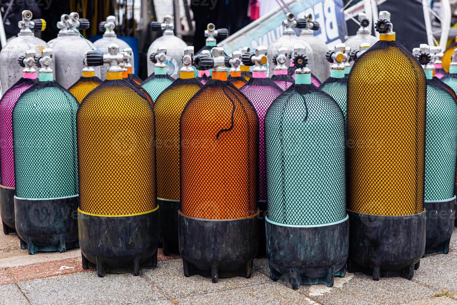 Colorful scuba diving tanks lined up at a dive shop in a coastal location during daytime. photo