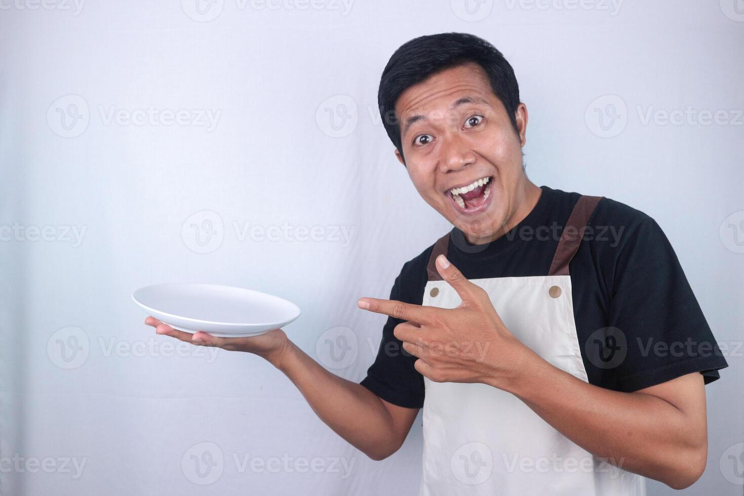 Happy face expression asian man chef or waiter shows empty white plate, presenting something photo