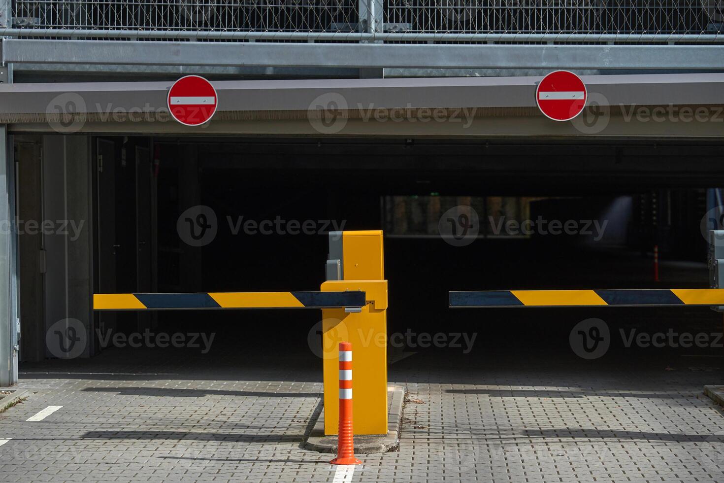 Parking spaces in the underground garage. entry and exit to the garage Barrier at the parking lot exit of a building. View of a car barrier gate at the entrance of a building. photo