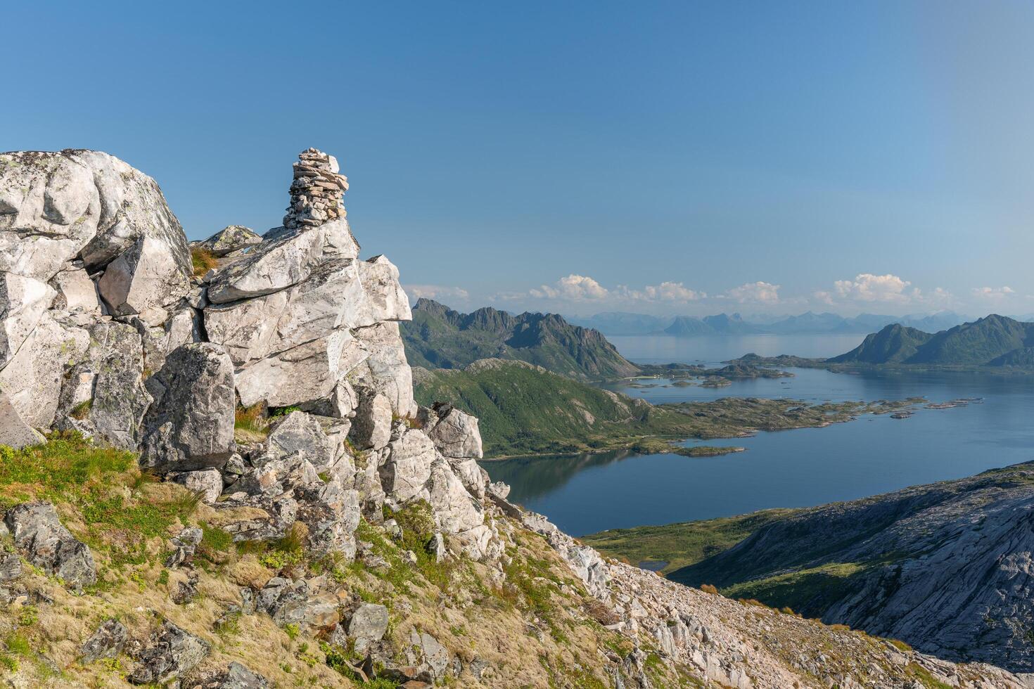 Rocky hill ridge with pyramid of stones on it and sea with islands in background, Lofoten Norway photo