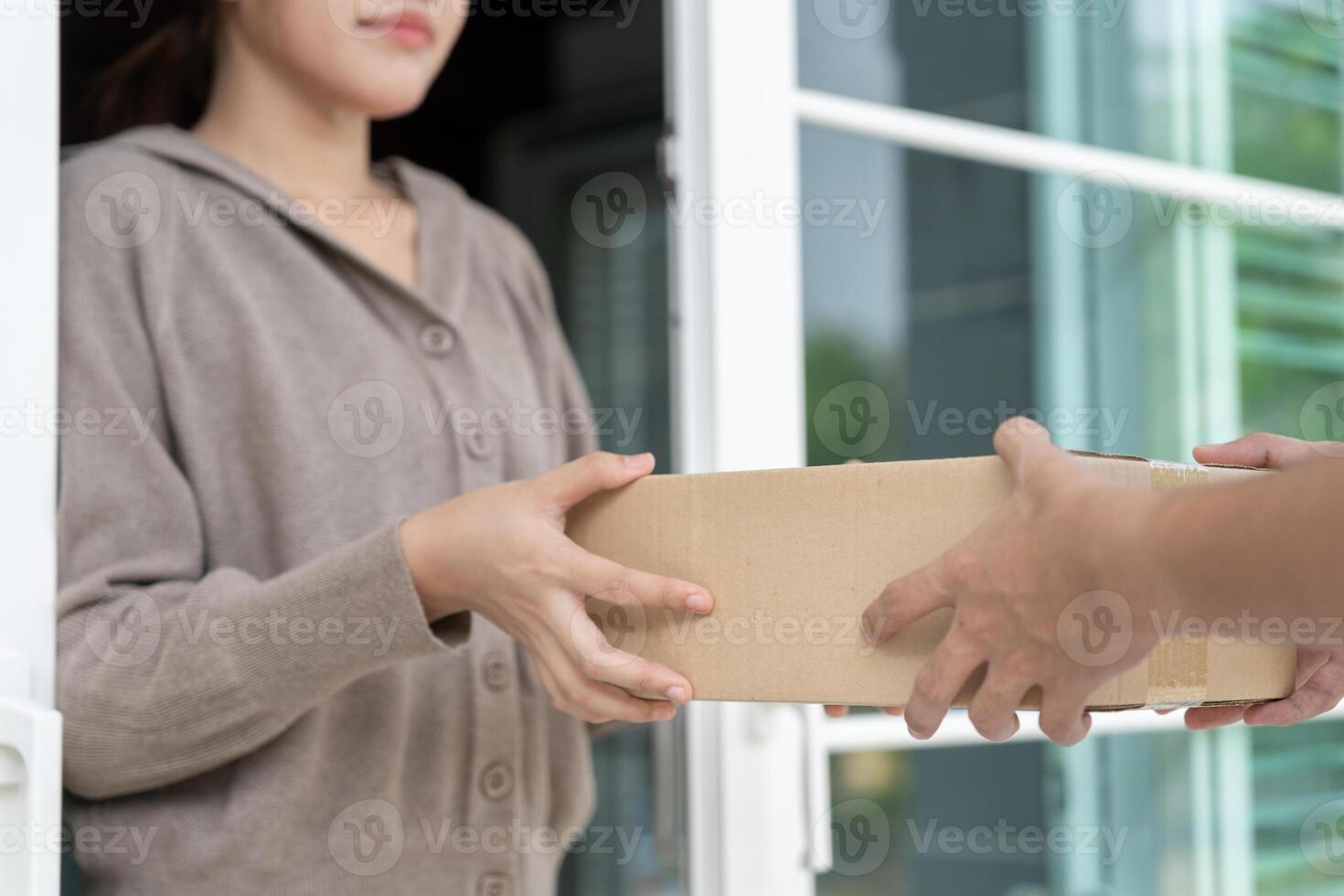woman receives box parcel from courier in front house. Delivery man send deliver express. online shopping, paper containers, takeaway, postman, delivery service, packages photo
