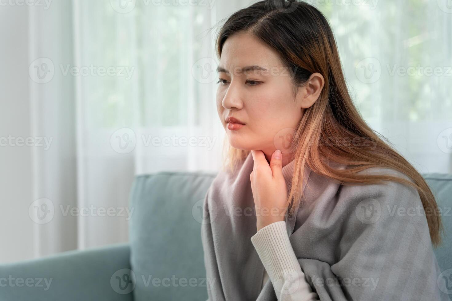 Asian woman put on neck due to a sore throat. female tonsillitis causes a inflammation. treated by taking water, taking antibiotics, consult a doctor, virus, corona virus photo