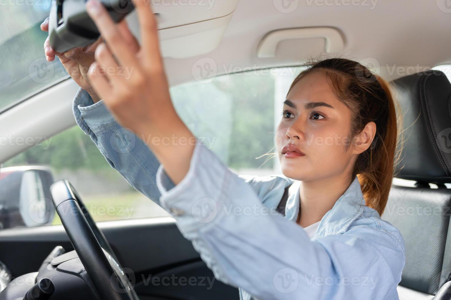 woman adjust car rearview mirror before drive, drives with intent, safe drive, driving practice, cheerful woman sits comfortably in the driver seat with confidently , readiness for a journey photo