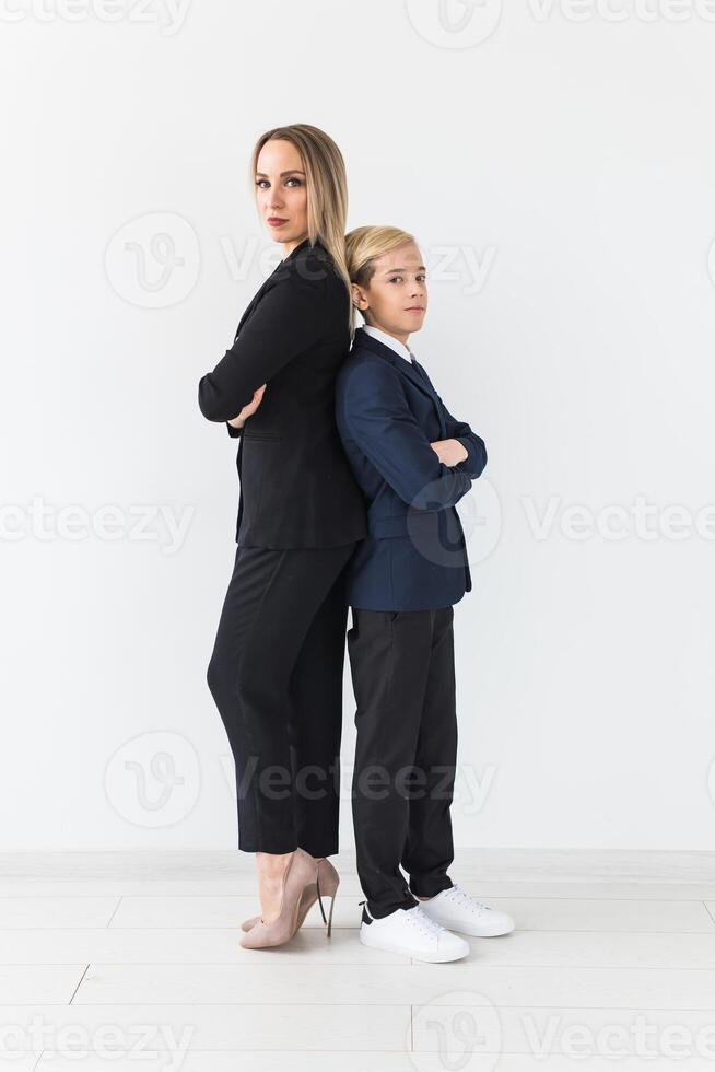 Teenager and single parent - Young mother and son standing together, back to back on white background. photo