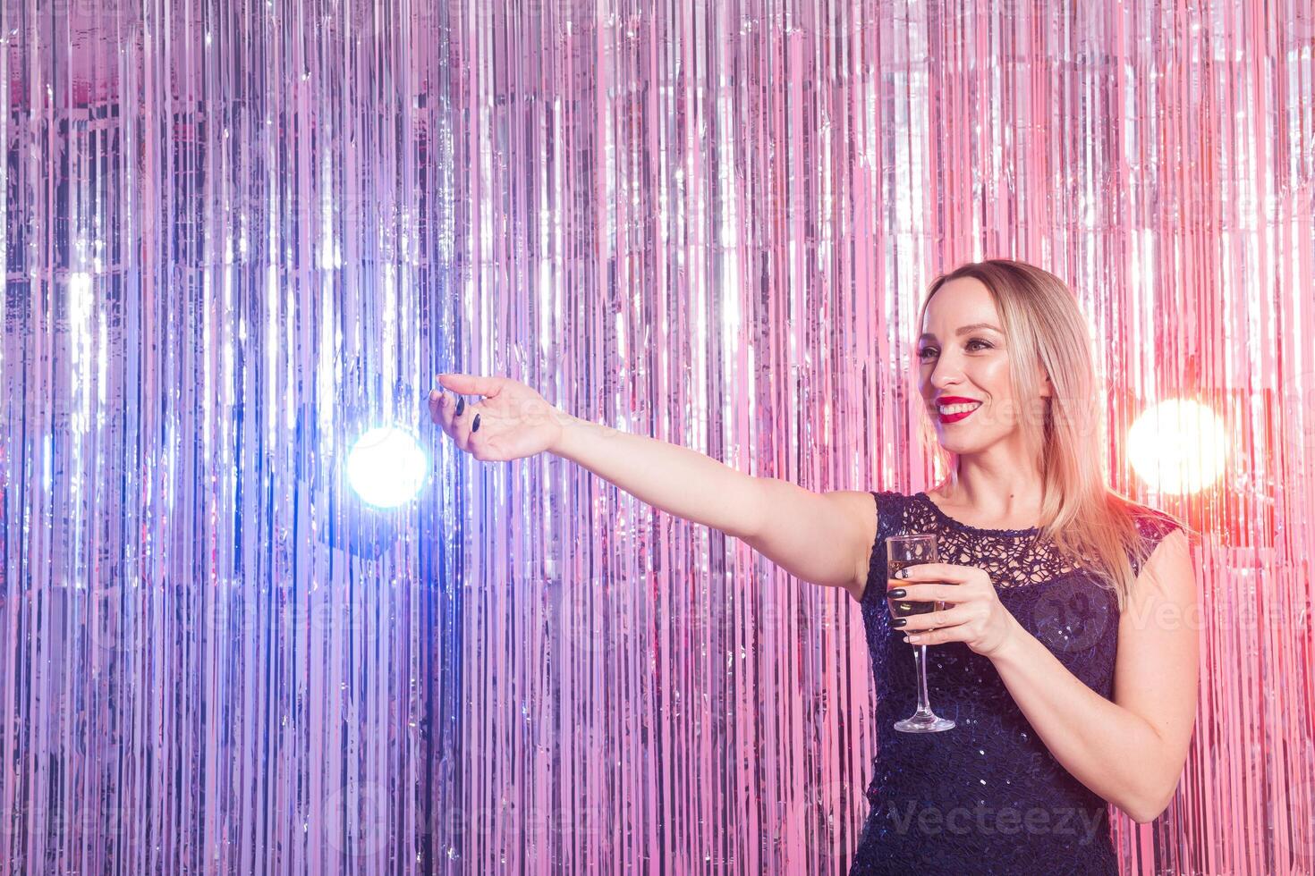 Party, drinks, holidays and celebration concept. Woman in evening dress with glass of sparkling wine over shiny background. photo
