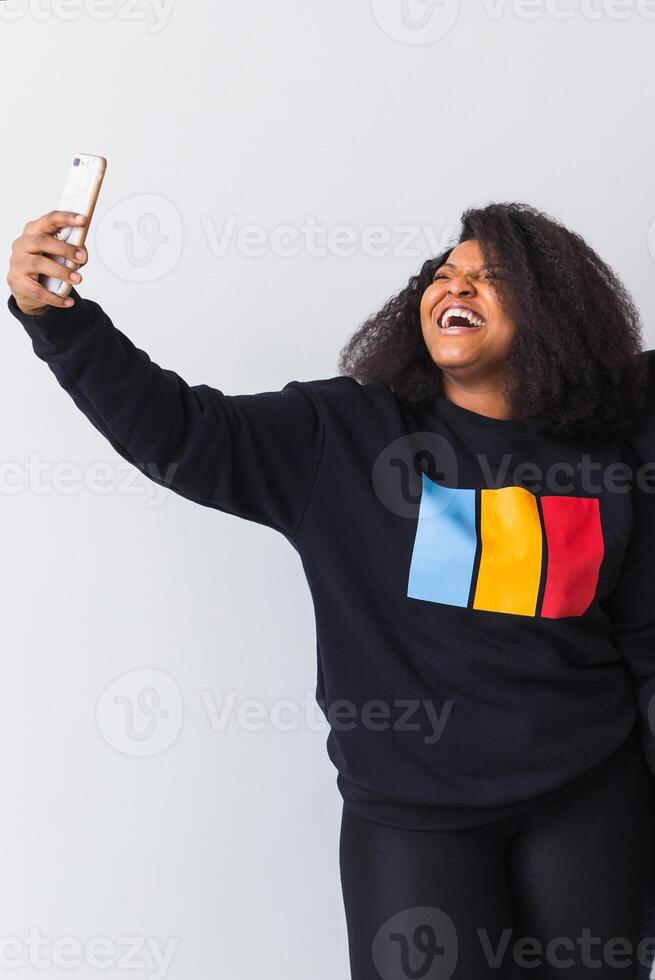 Happy afro american woman taking selfie in studio on white background. photo