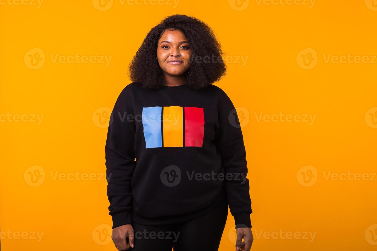 Young beautiful african american girl with an afro hairstyle. Portrait on yellow background with copy space. Girl looking at camera. photo