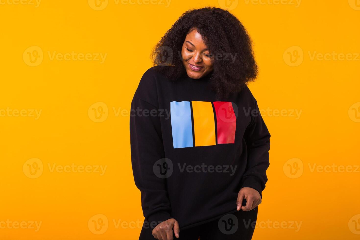 Young beautiful african american girl with an afro hairstyle. Portrait on yellow background with copy space. Street fashion. photo