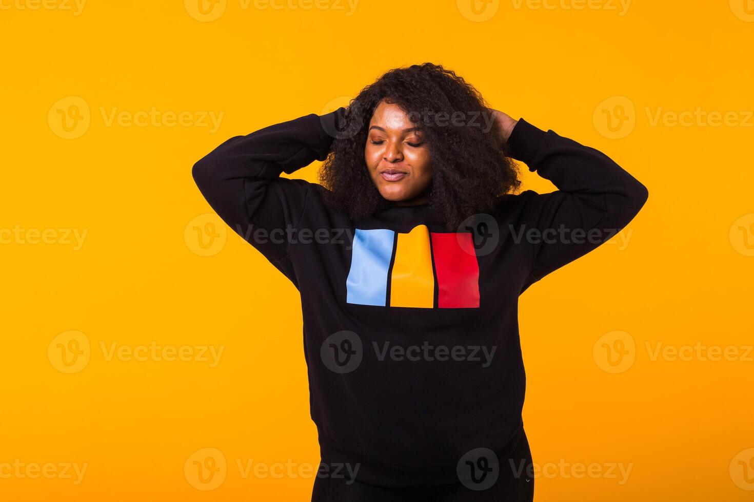 Young beautiful african american girl with an afro hairstyle. Portrait on yellow background. Girl looking aside. Street fashion. photo