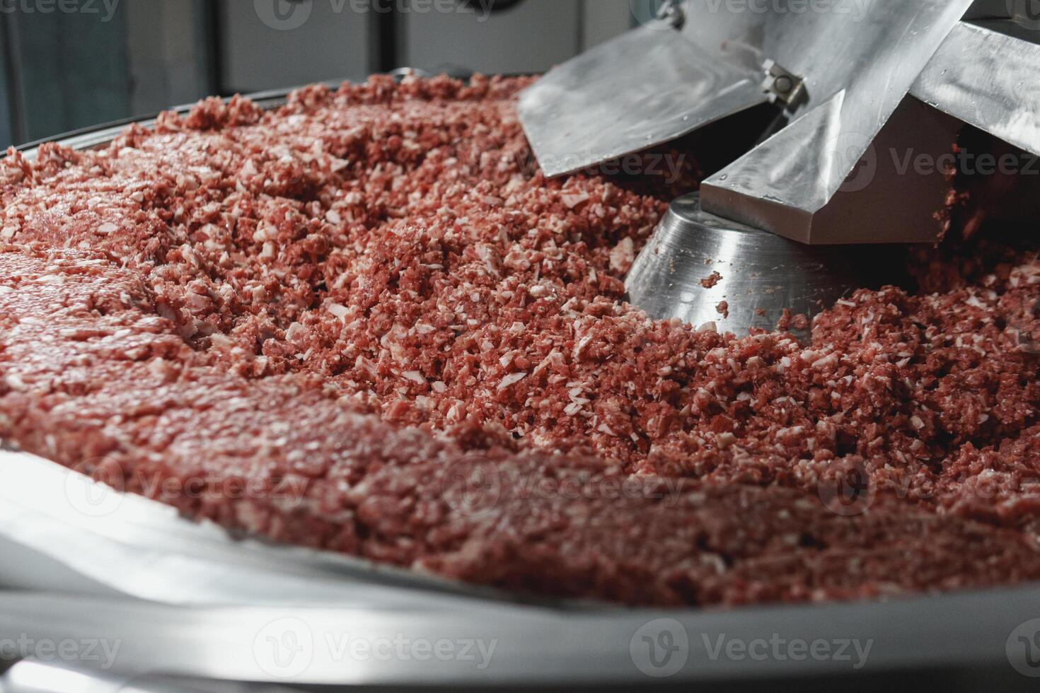 Processing of production minced meat in industrial meat grinder, close up photo