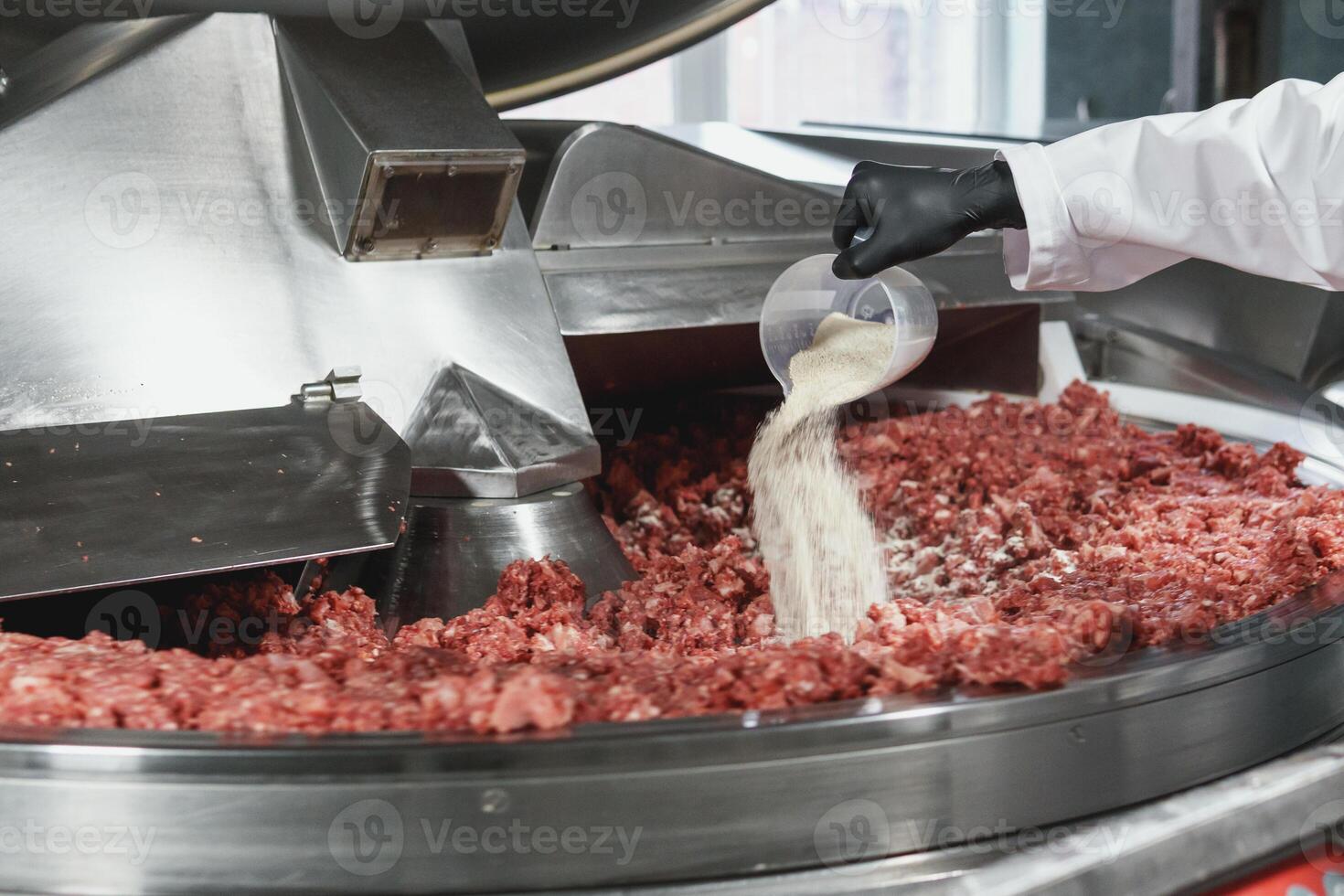 Processing of production minced meat in industrial meat grinder, close up. Modern technologies in Food industry photo