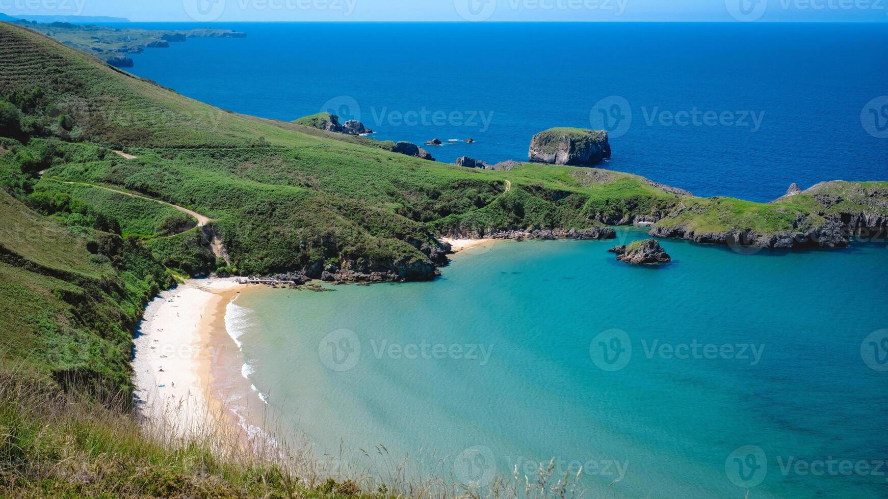 Scenic view of a hidden beach in Asturias, north Spain, cove with turquoise water and lush green cliffs on a clear summer day photo