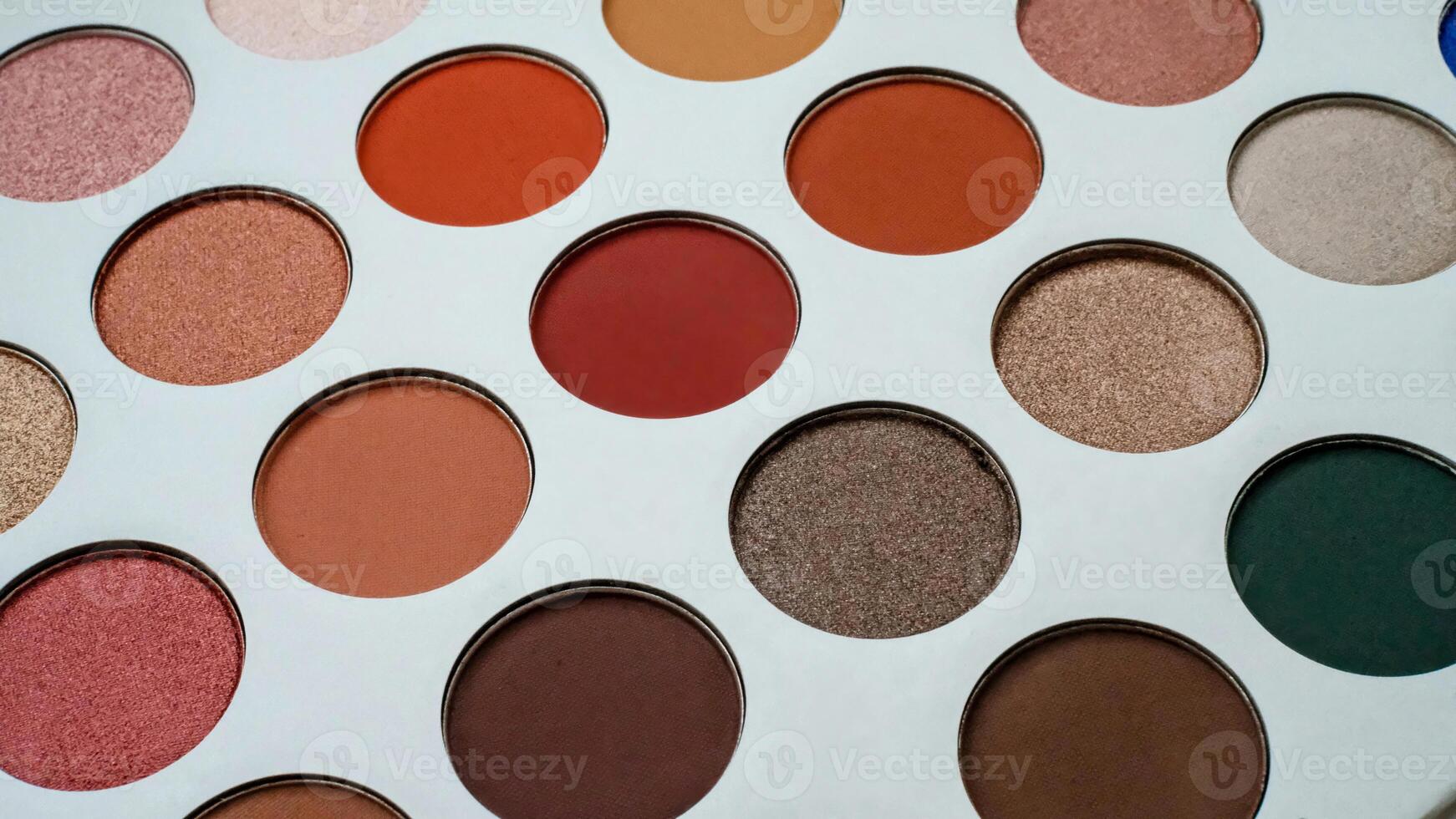 Close-up of a colorful makeup eyeshadow palette with a variety of matte and shimmer shades in warm and neutral tones. photo