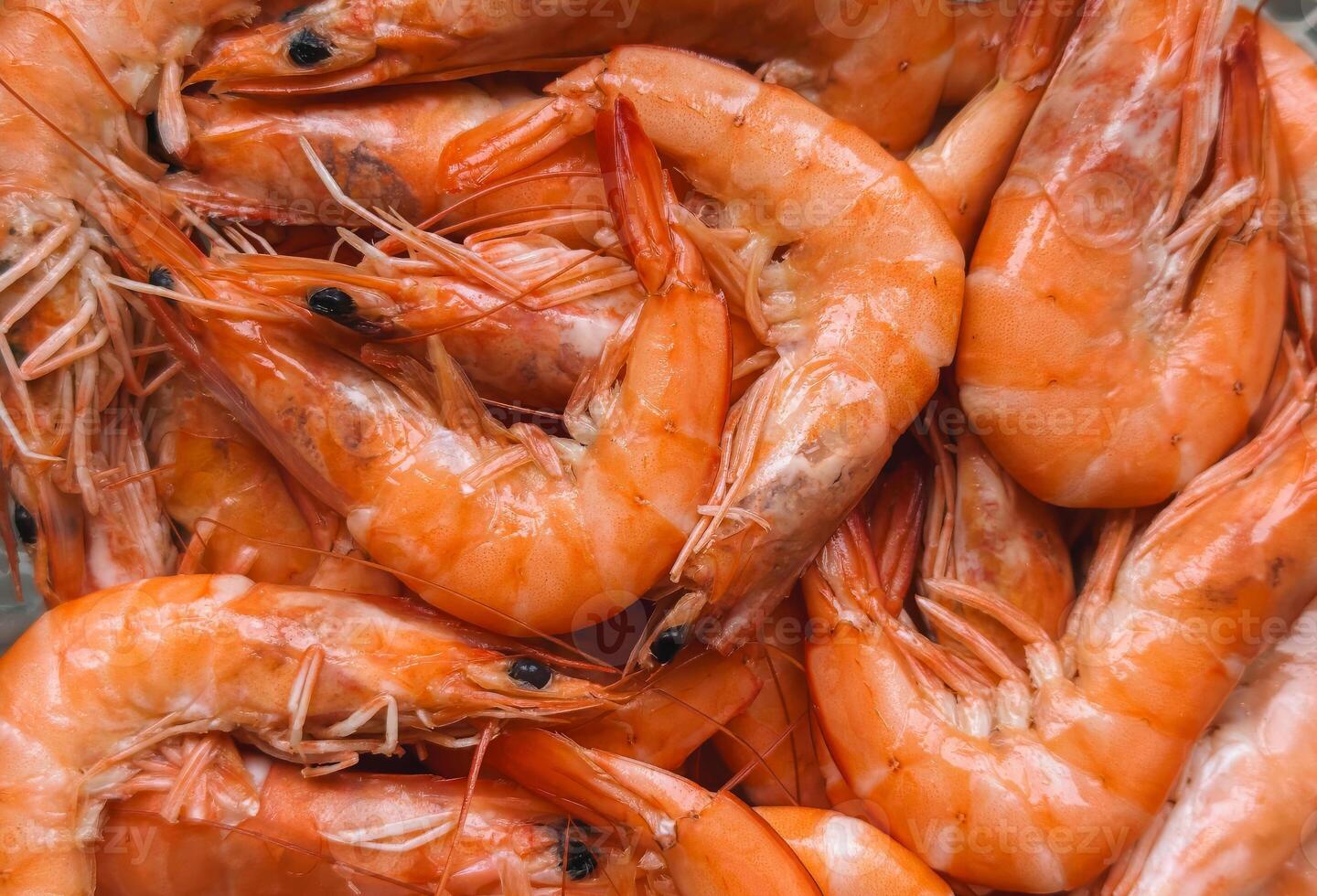 Close-up of a pile of fresh, cooked shrimp with vibrant orange shells and detailed textures photo