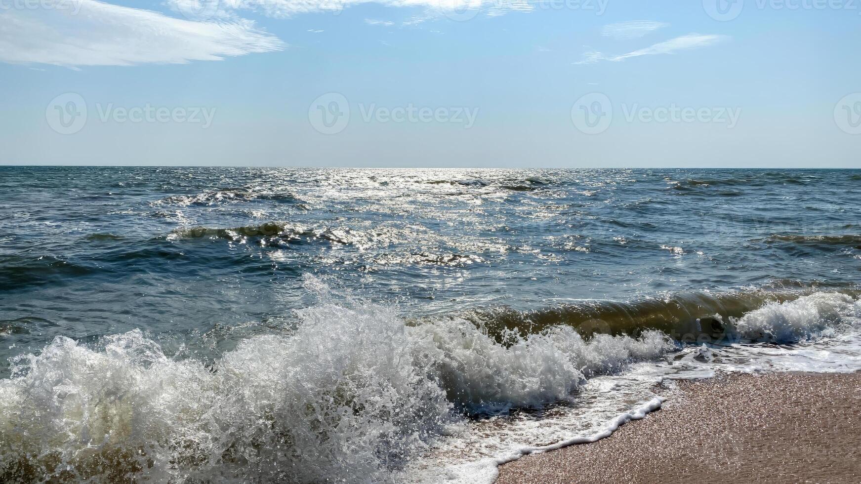 Dynamic close-up view of ocean waves crashing onto the sandy beach under a bright sun photo