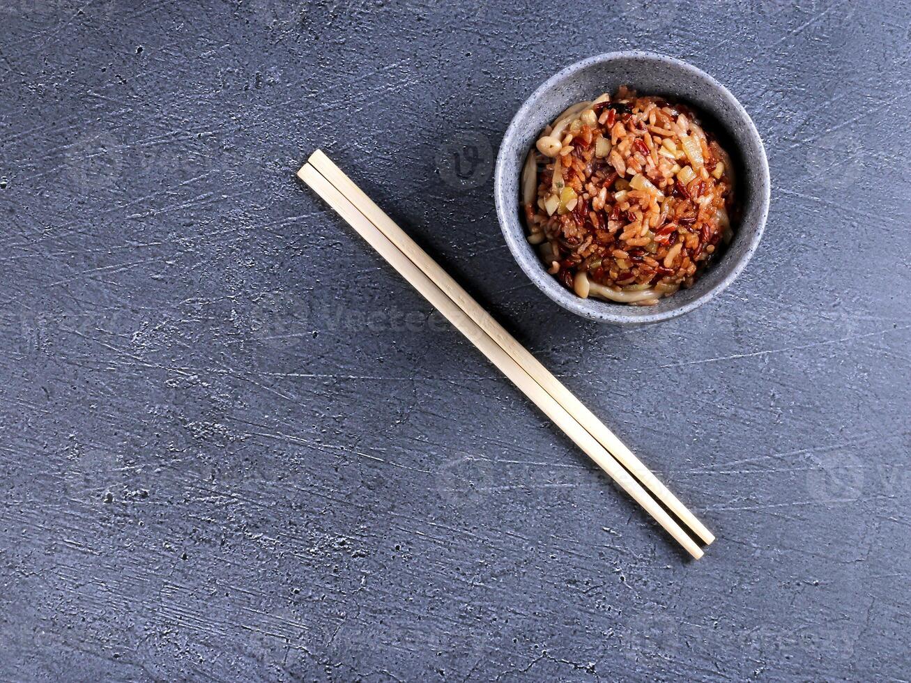 chopsticks and bowl of food on a gray surface photo