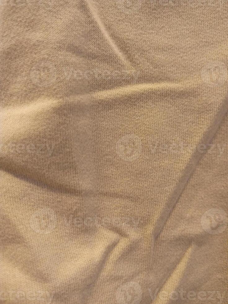 Close-up of beige cotton fabric with soft wrinkles. Ideal textile background for design or template. photo