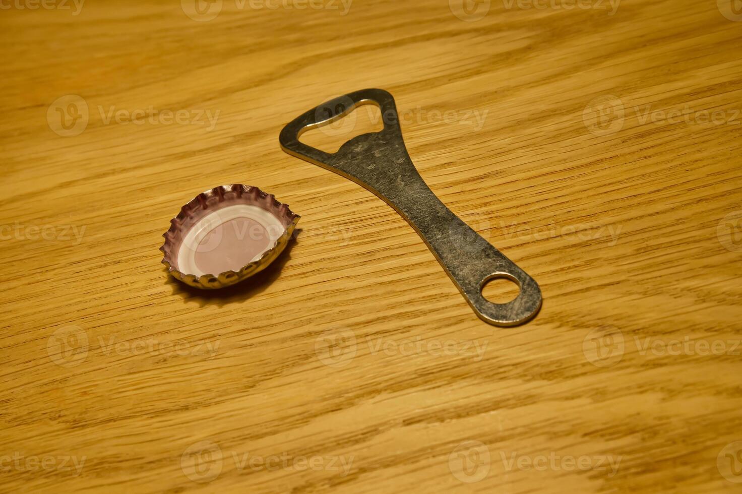 Bottle Opener and a Cap on Wooden Surface photo