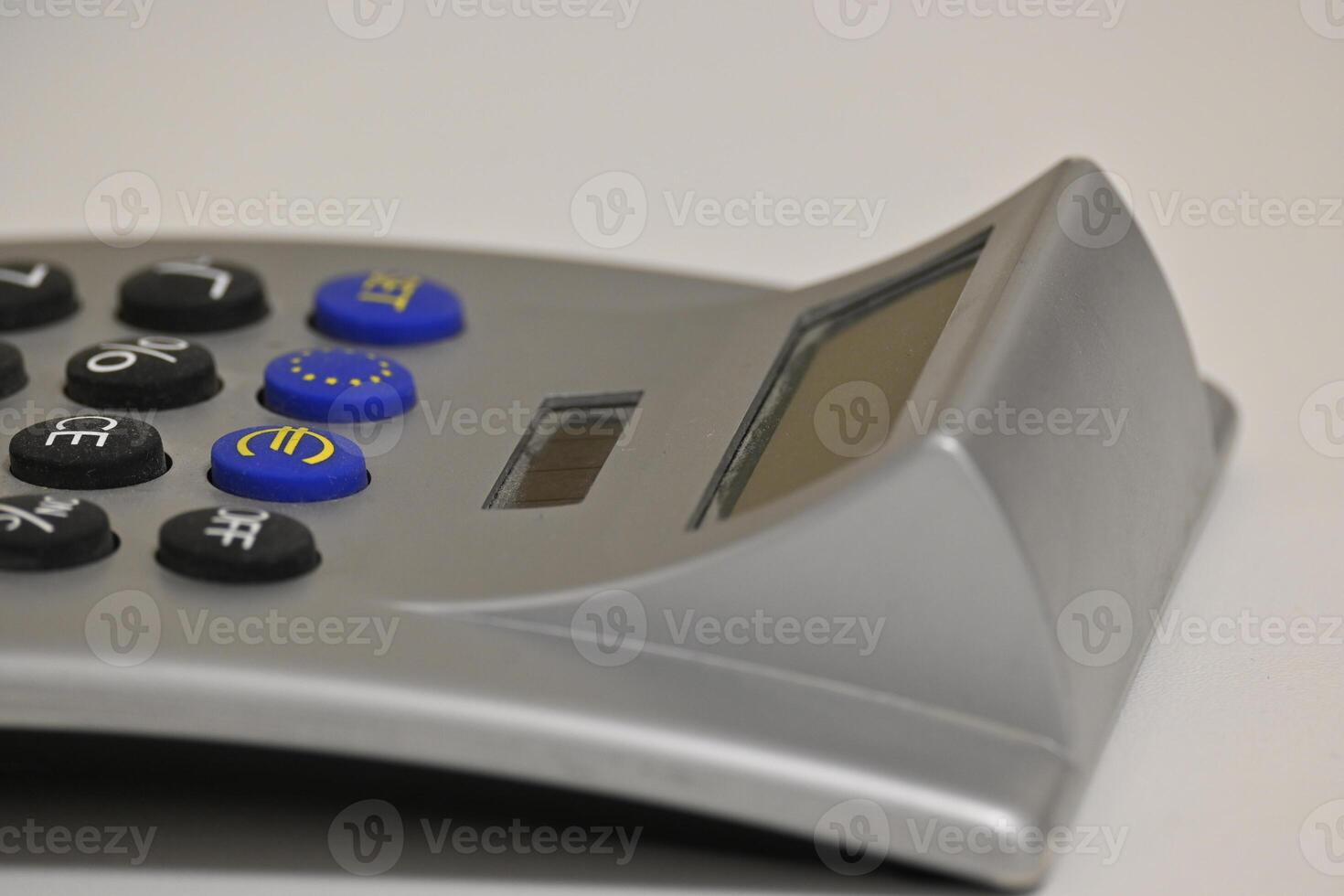 A calculator with solar cells and keys with the focus on the Euro sign against a grey background photo