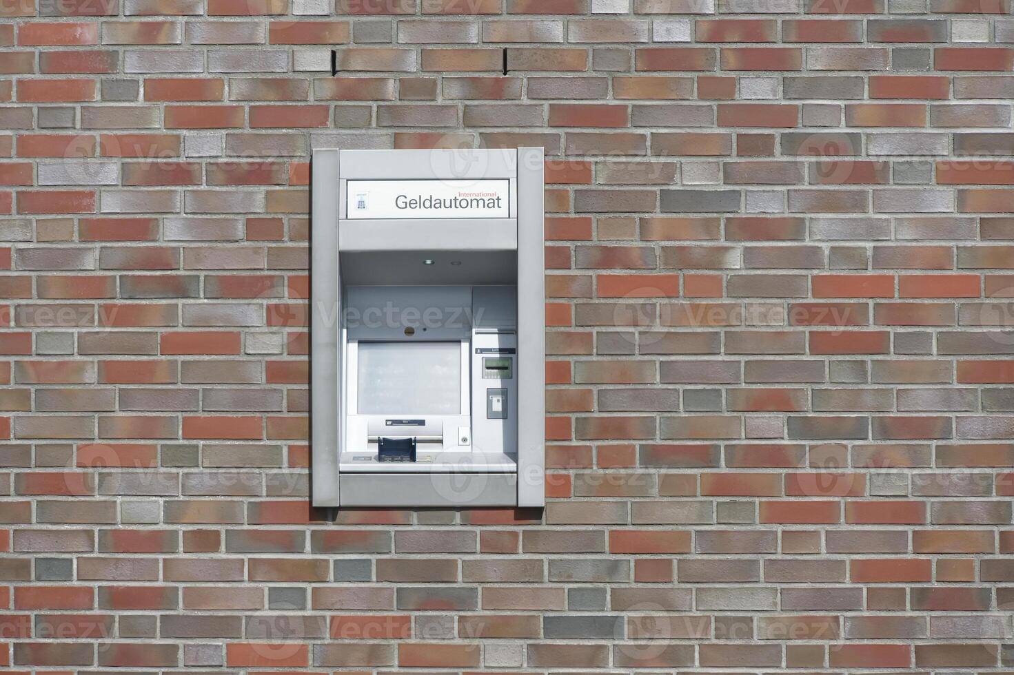A German ATM is embedded in a wall of brown-red clinker bricks to withdraw money with EC Visa Mastercard credit card photo