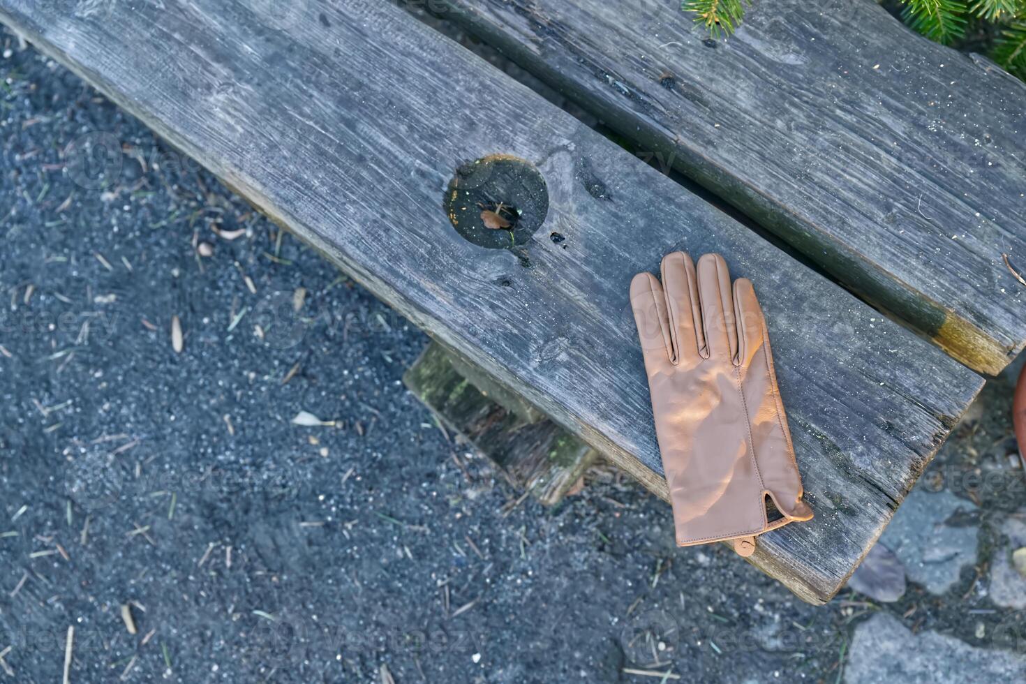 Brown Leather Glove on Rustic Wooden Bench photo