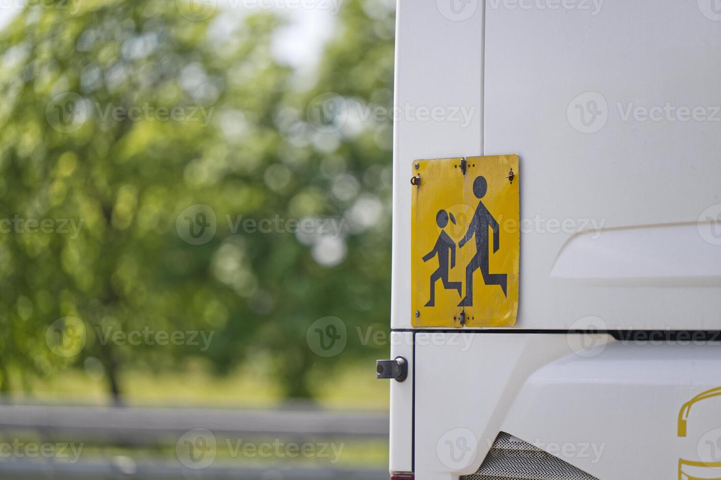 Yellow and black sign at the rear of the school bus warns of running students photo