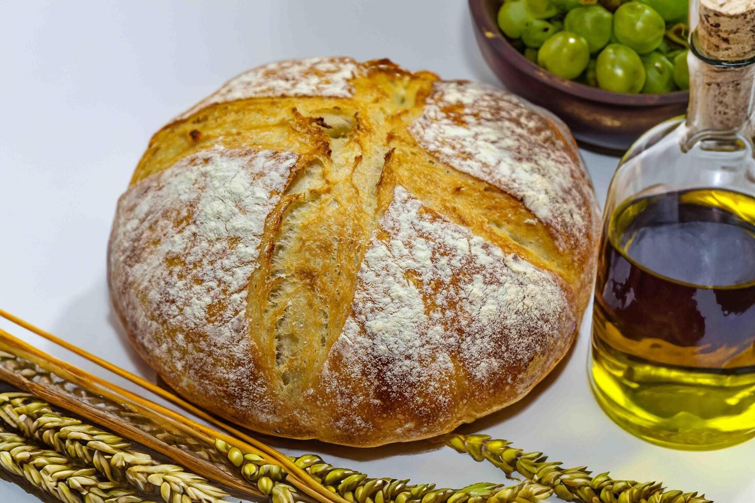 Catholic sacred table with rustic bread, olive oil, wine, grapes, rosary and ears of wheat. The body and blood of Christ closeup photo