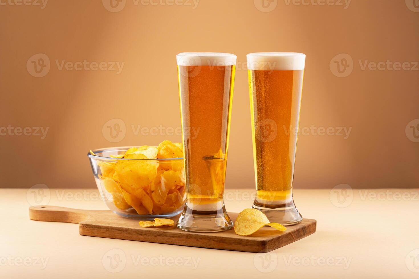 Crispy potato chips in glass bowl with two cold beers on wooden tray against warm background. Concept of bar snack, social drink and casual beer pairing. Beer and chips reflect comfort and taste photo