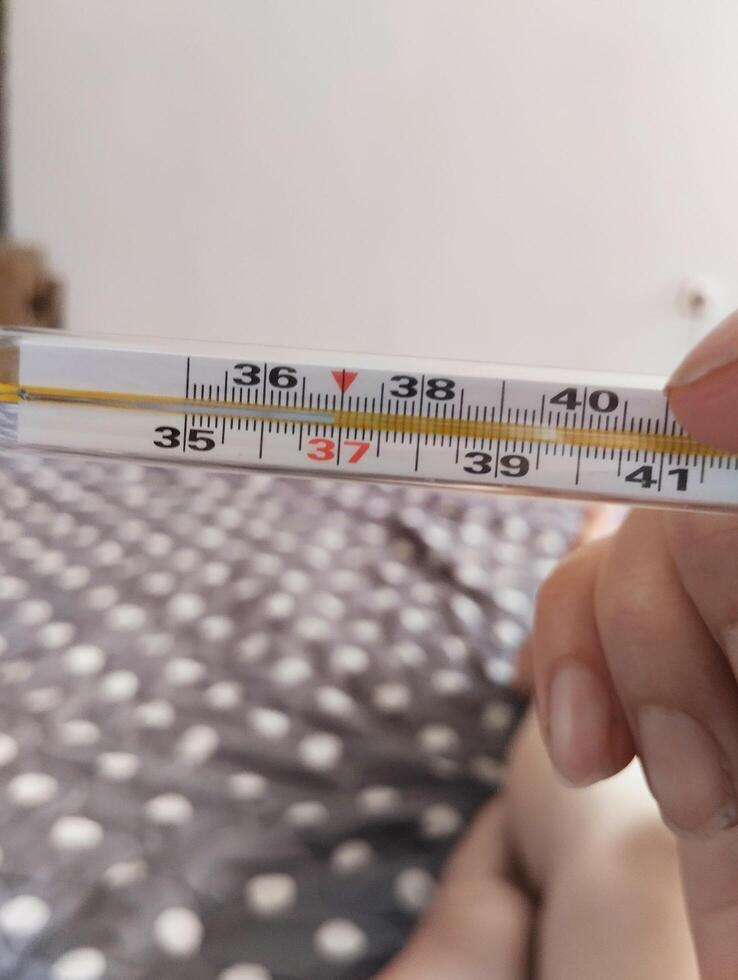 He holds a mercury thermometer in his hands with a high temperature. Illness malaise photo