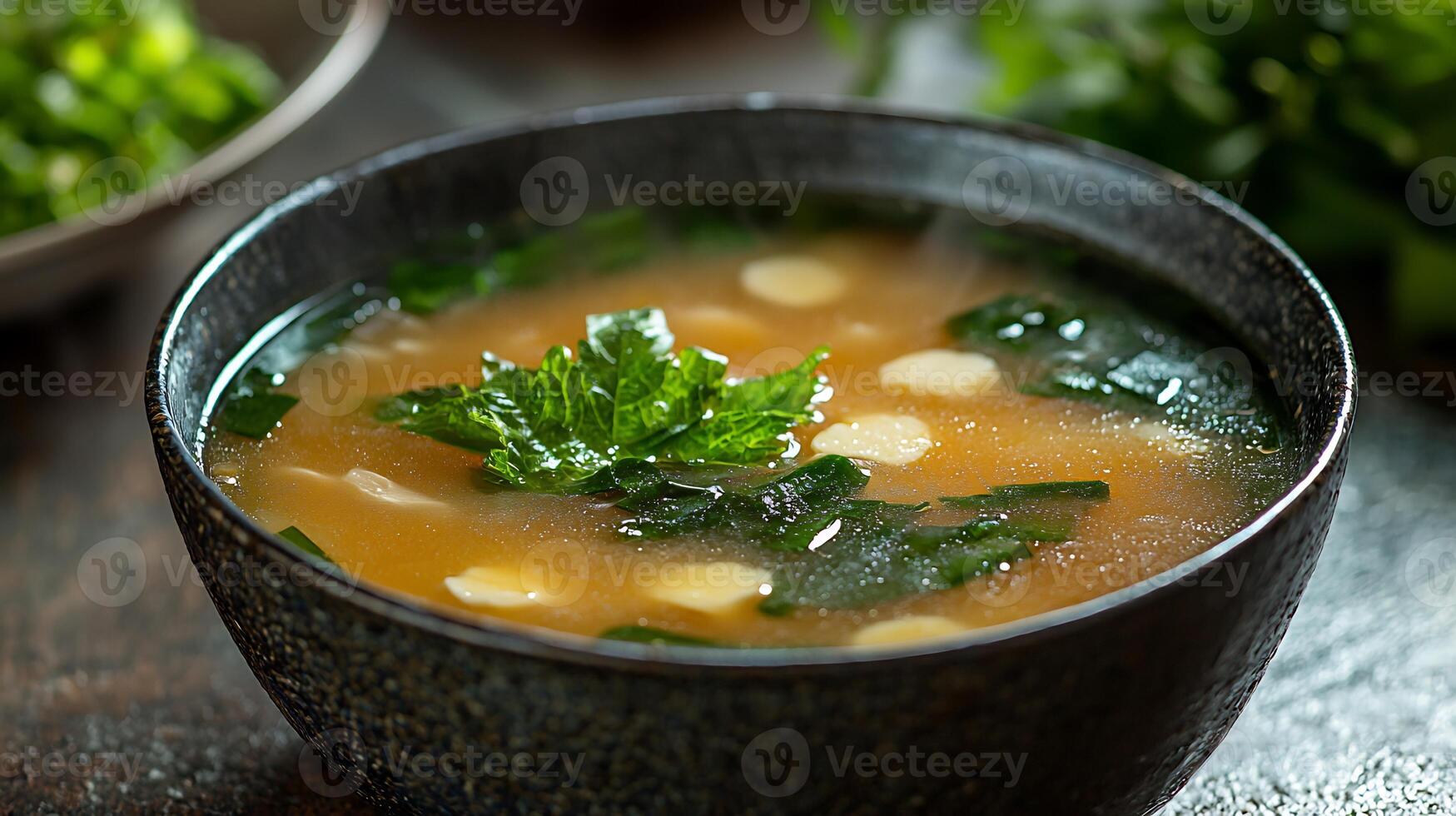 A bowl of soup with a spoon and some herbs photo