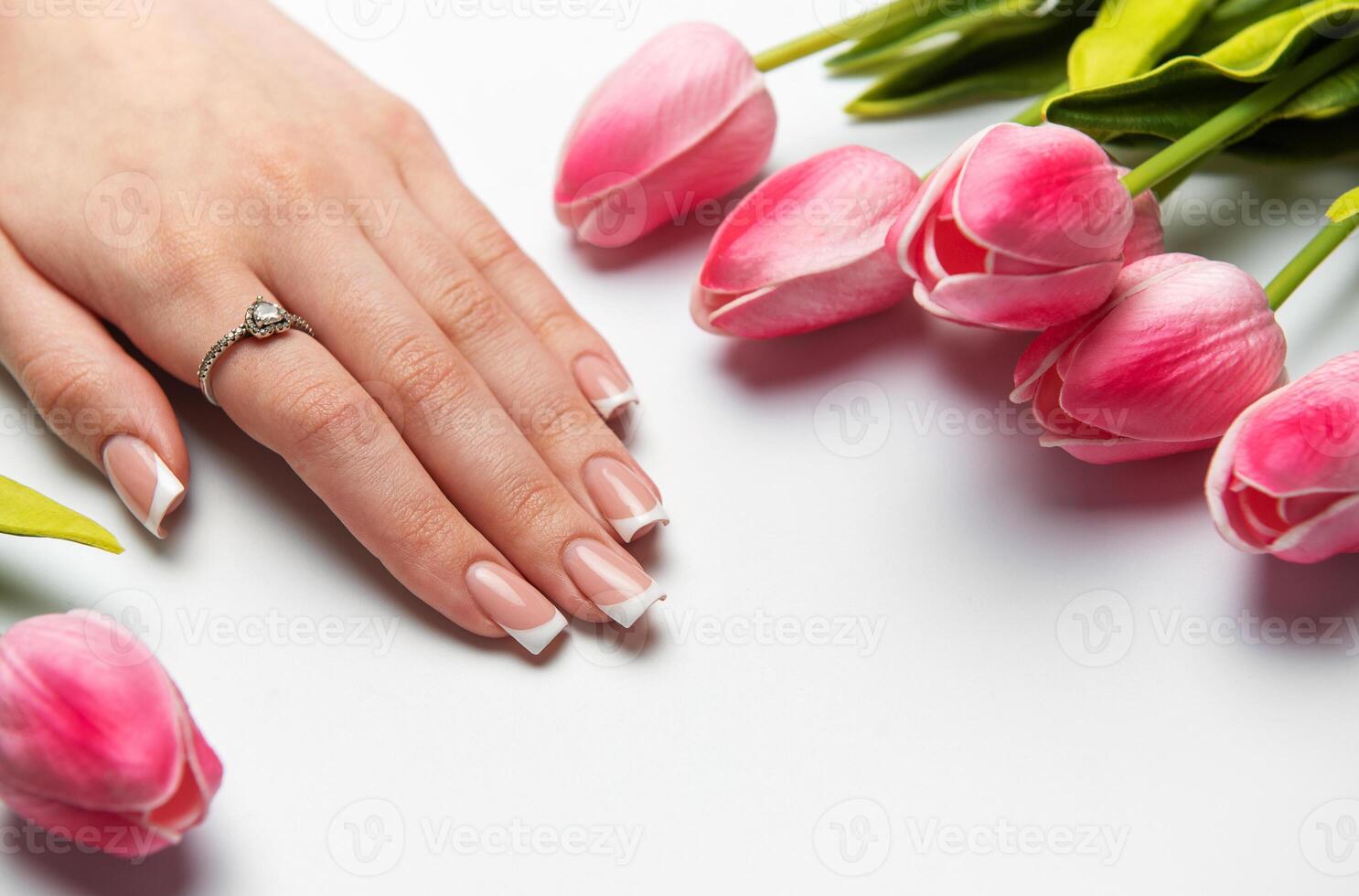Woman showing manicure near pink tulips on white background photo