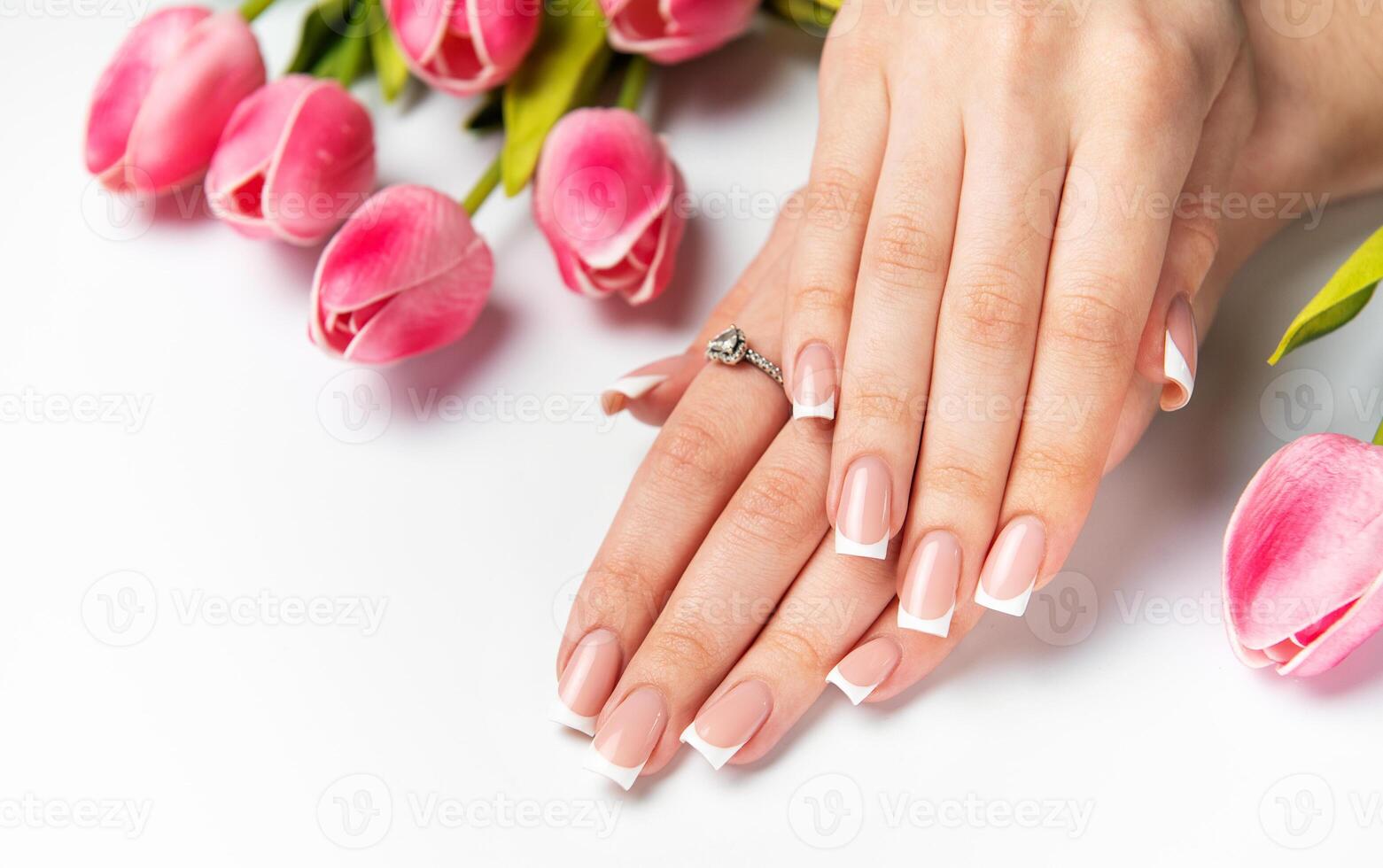 Woman showing french manicure and pink tulips on white photo