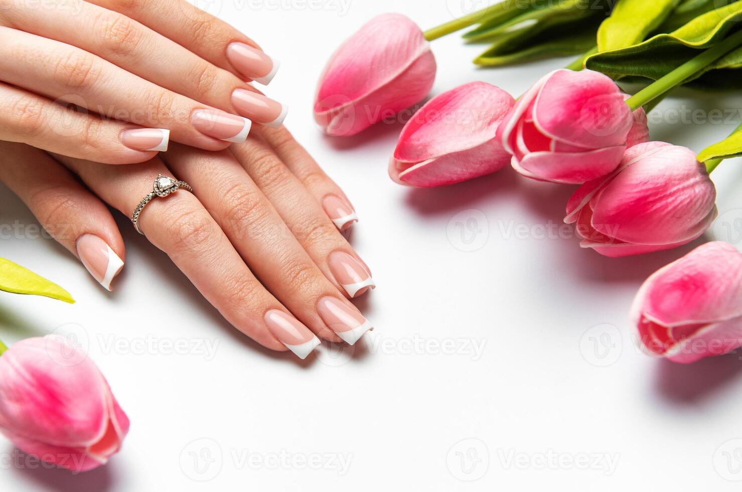 Woman with french manicure and pink tulips on white background photo