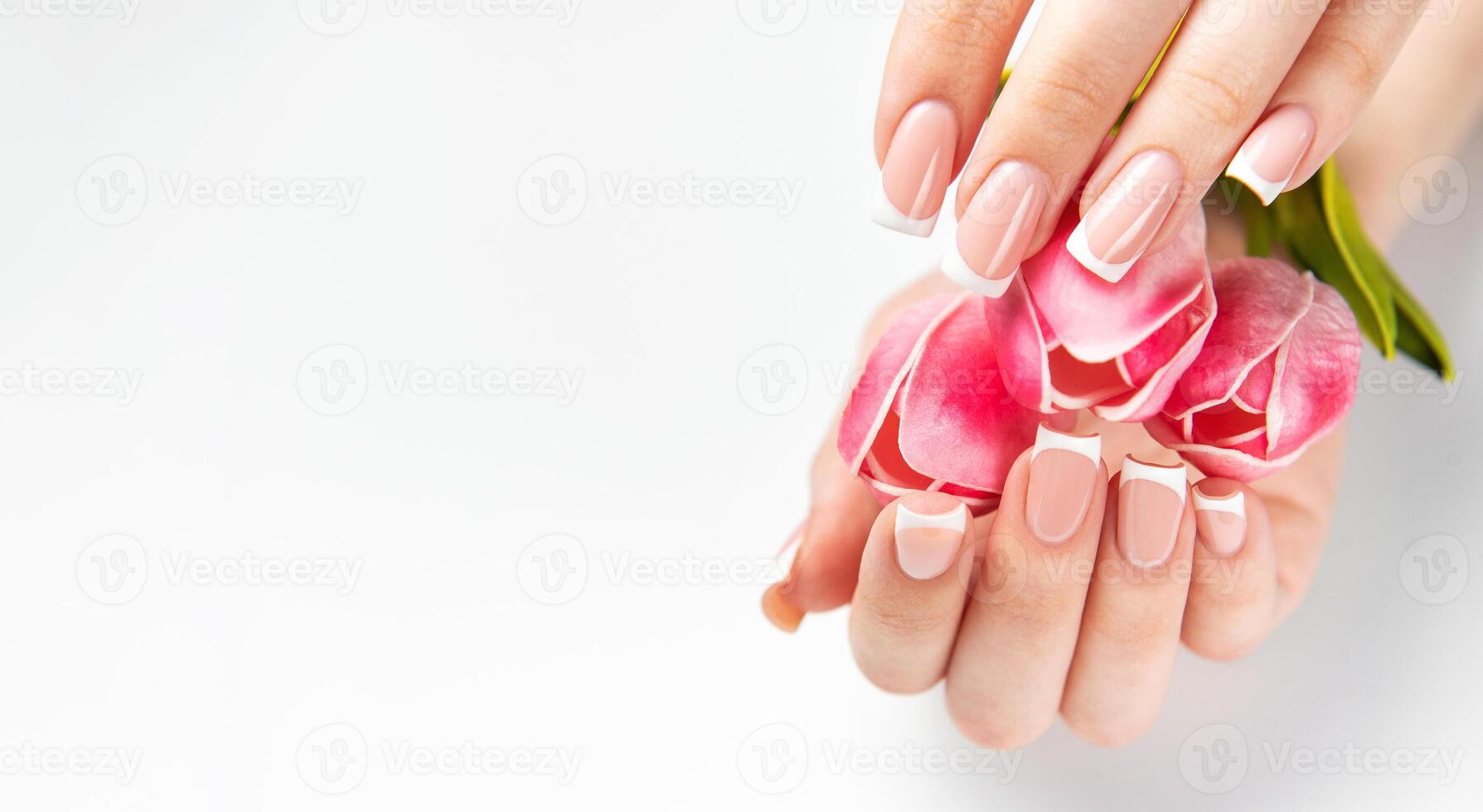 Woman showing french manicure holding pink tulips photo