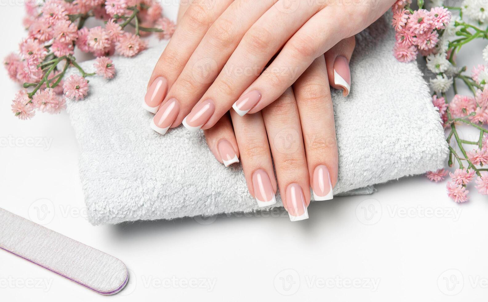 Woman showing her french manicure on a white towel photo