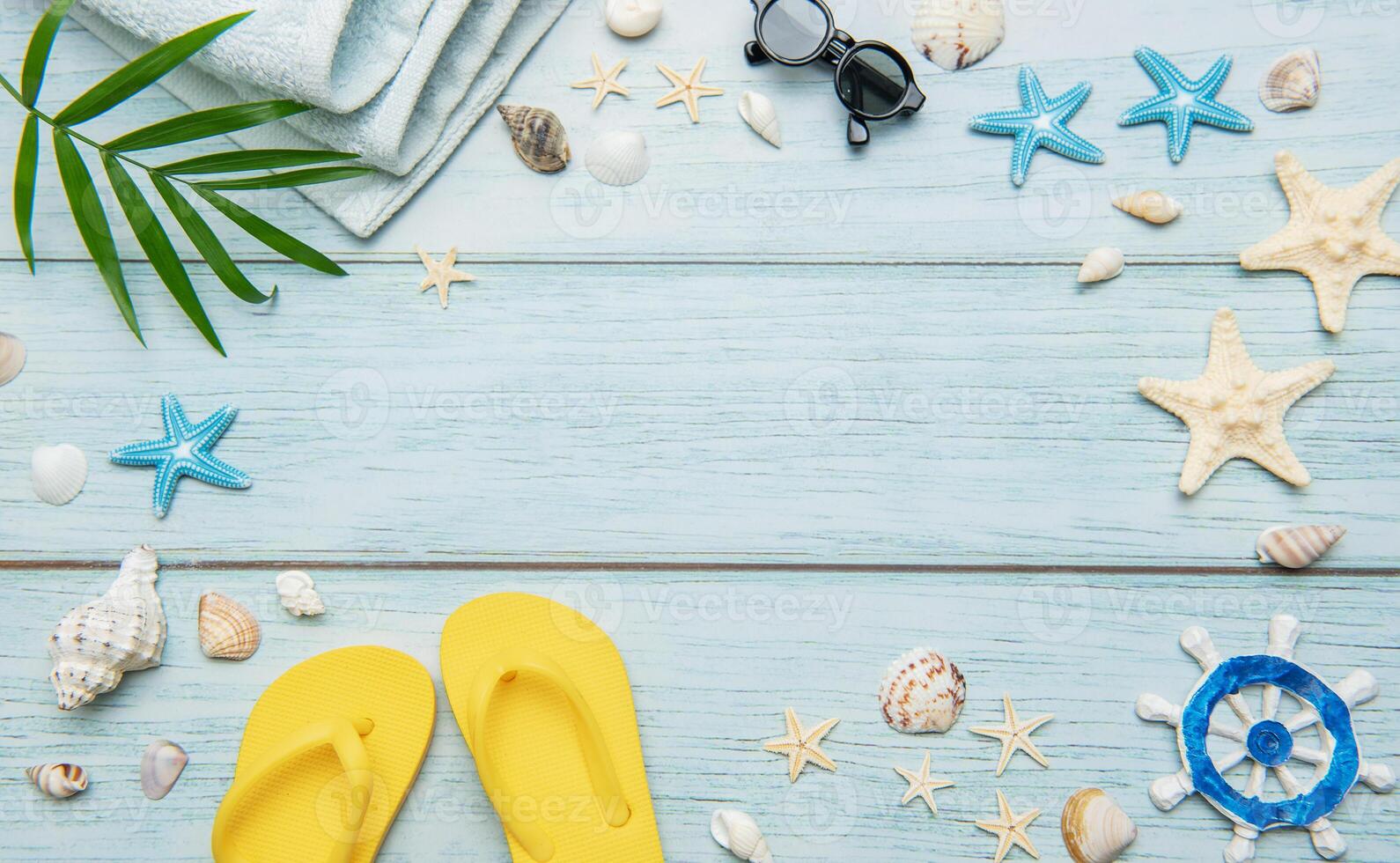 Summer essentials creating a frame on a light blue wooden background, ideal for travel and vacation themes photo