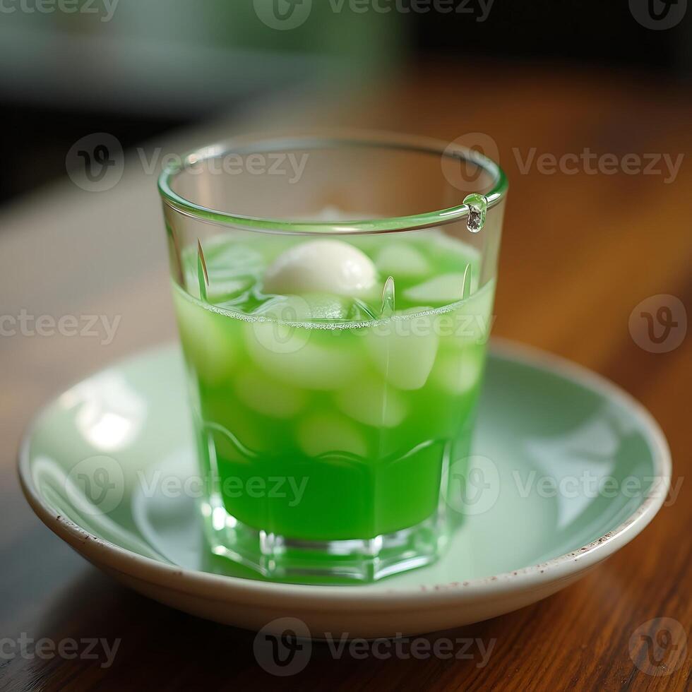 Green Drink with White Spheres in Glass on Saucer Close Up photo