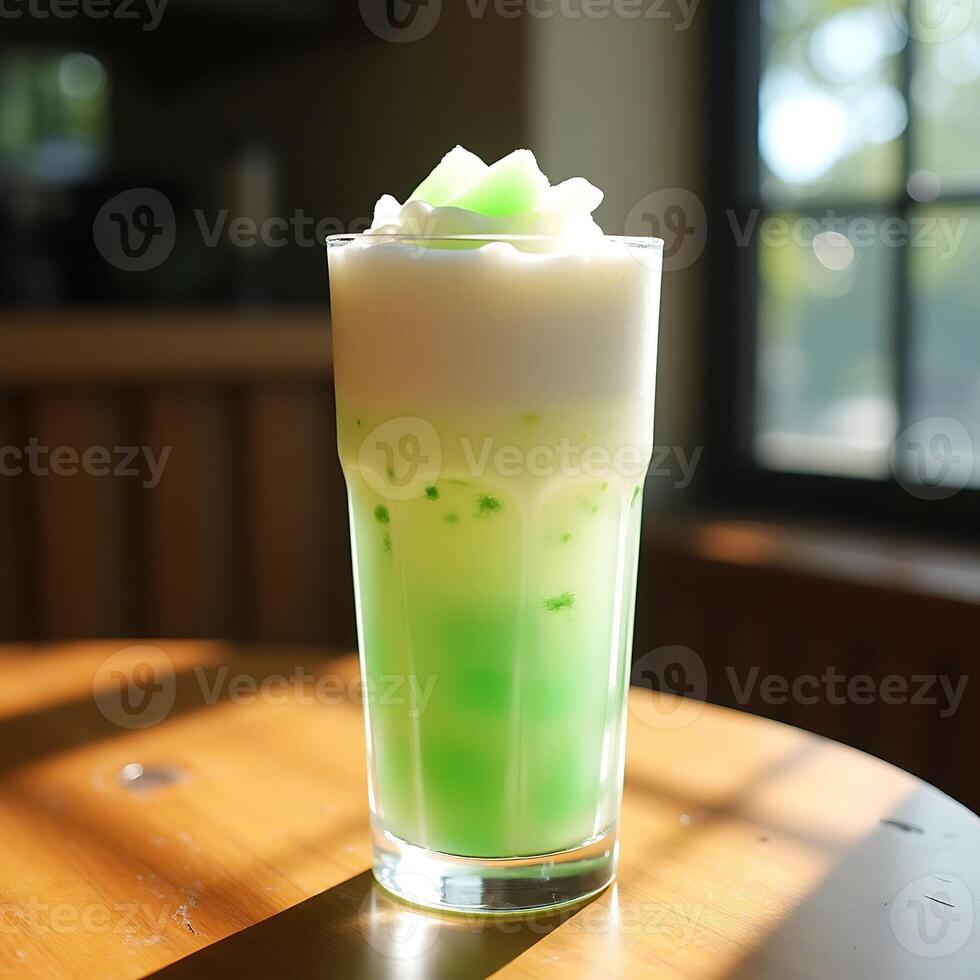 Refreshing Green Drink with White Foam in Glass on Table photo