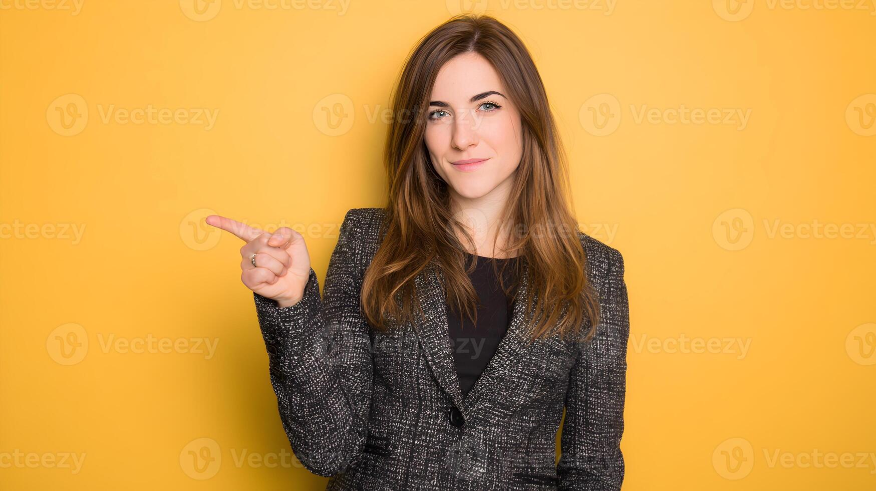 Woman in Grey Blazer Pointing to the Side Yellow Background photo