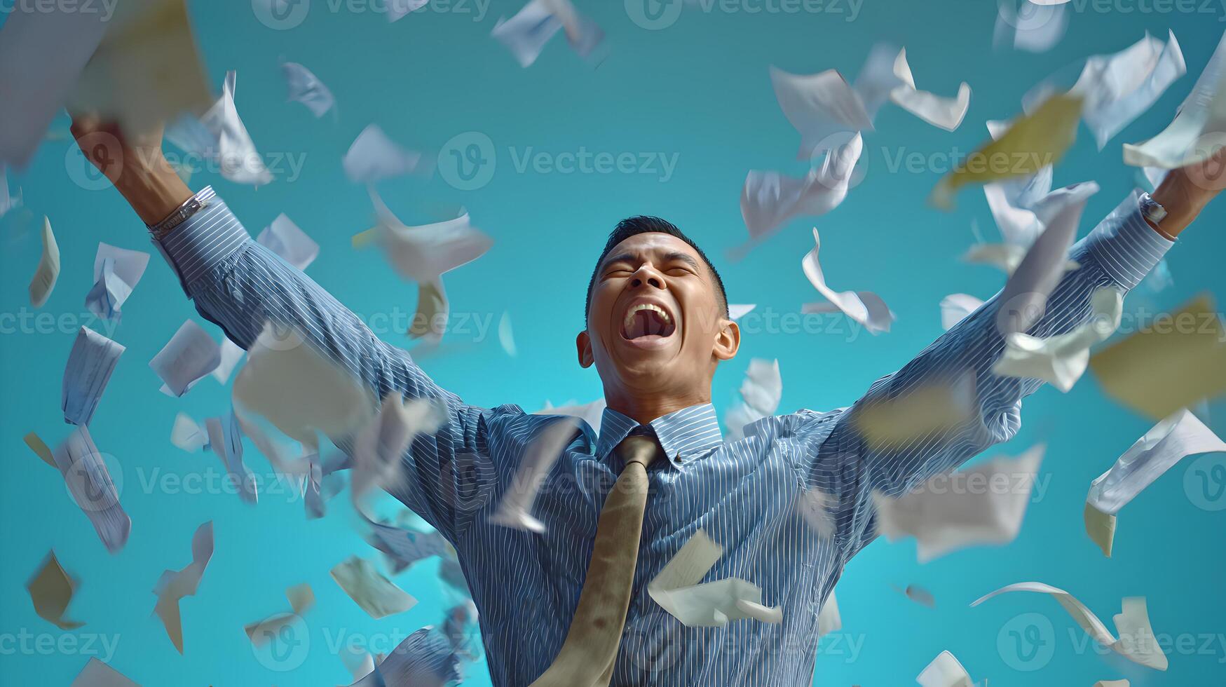 Joyful Businessman Celebrating Success Amidst Flying Papers Blue Background photo