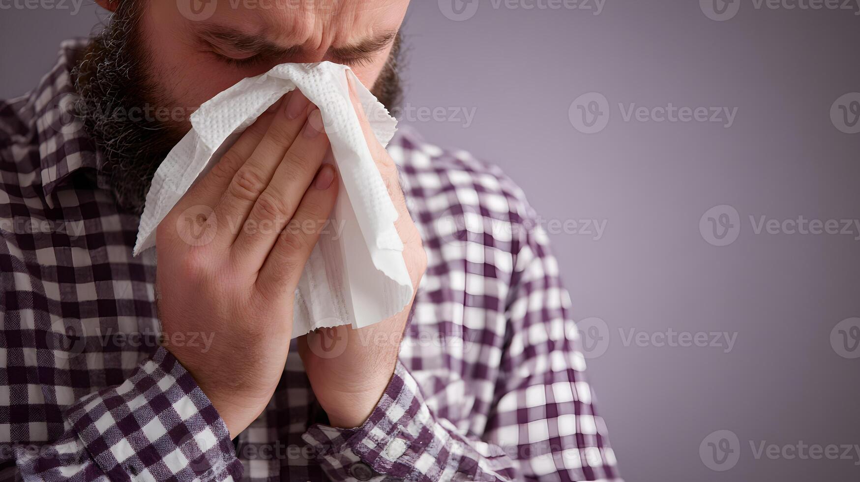 Man with Beard in Plaid Shirt Blowing Nose with Tissue photo