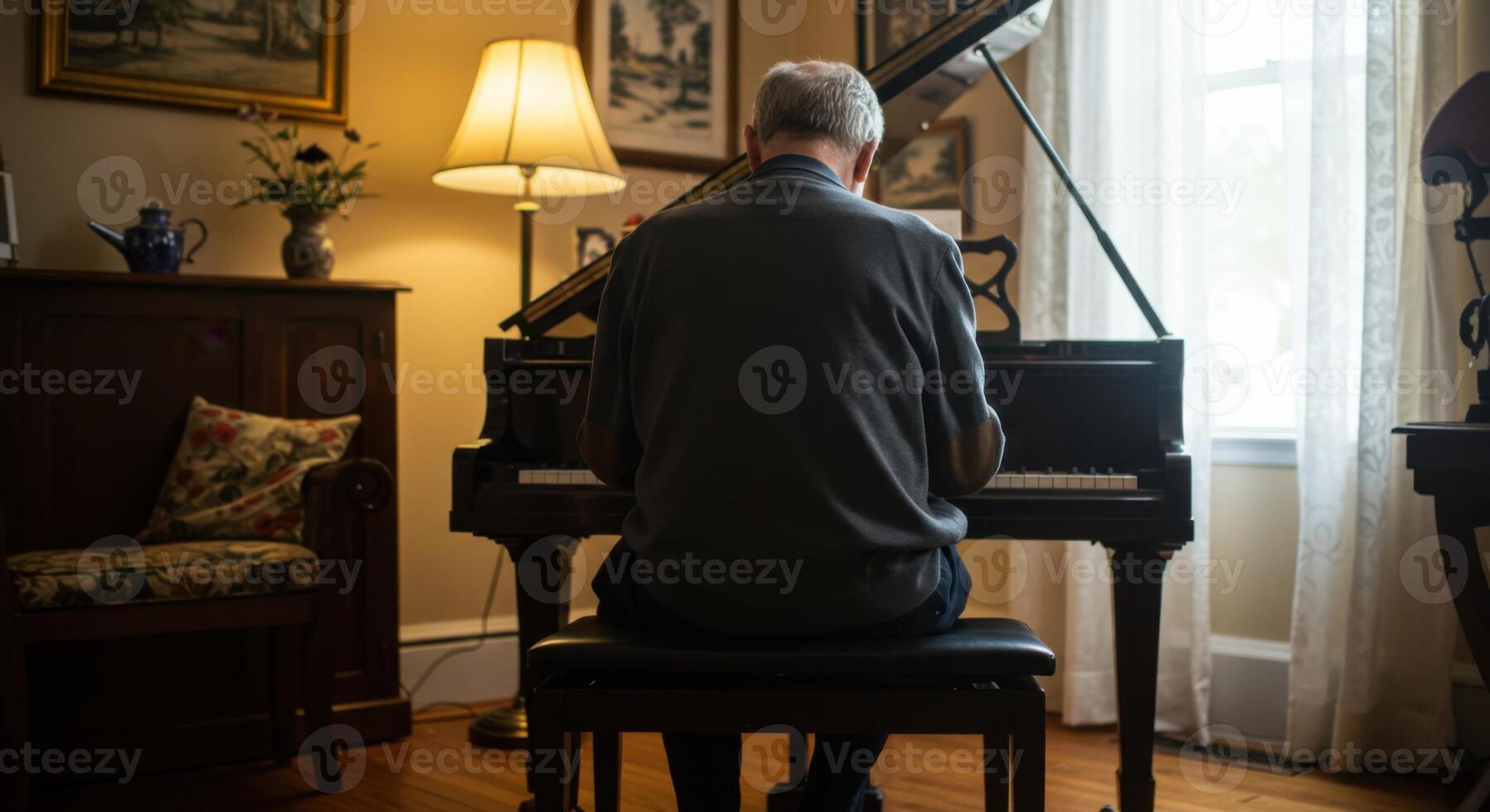 A senior man is seen from the back, playing a beautiful grand piano inside of a living room. photo