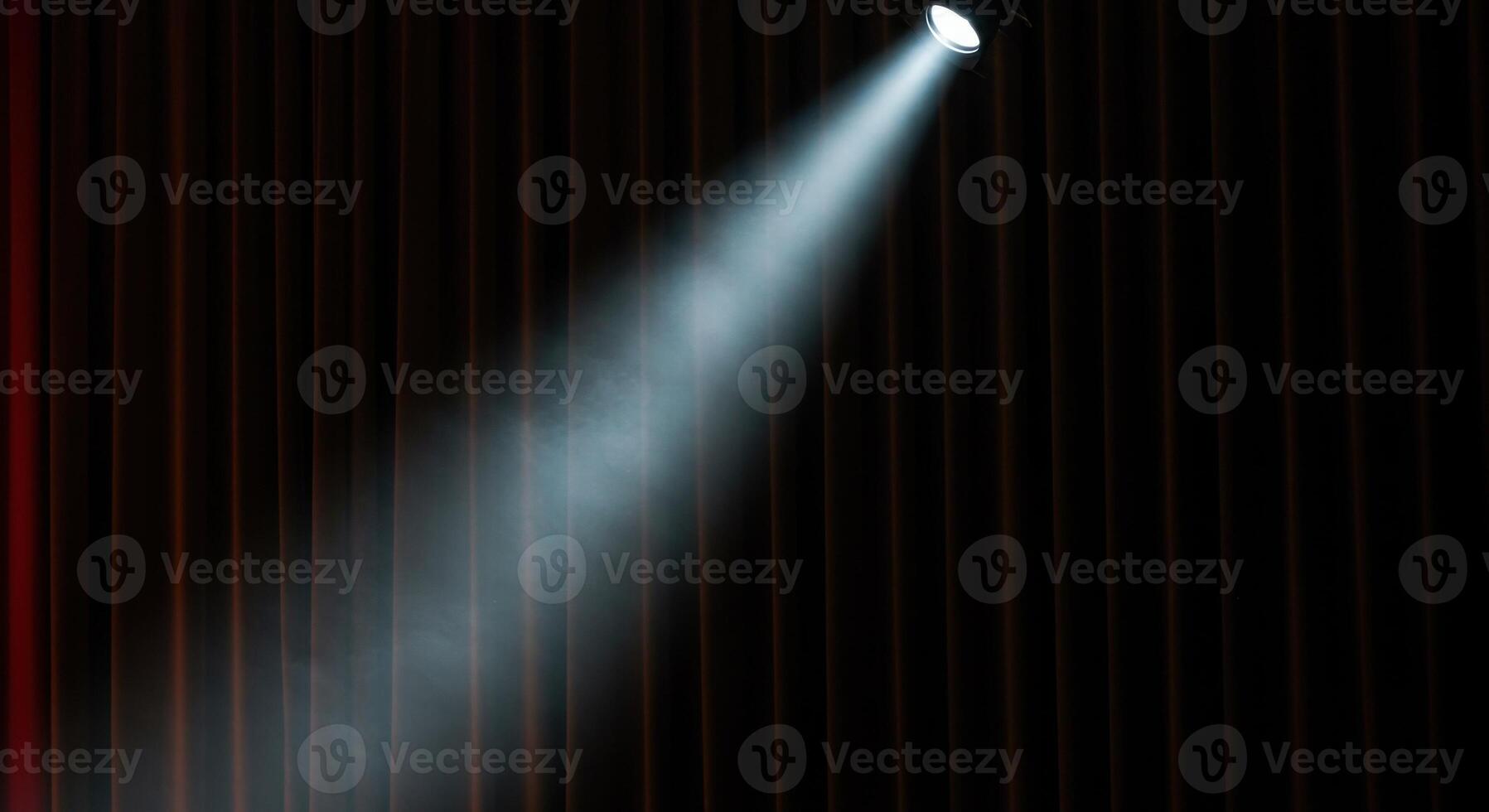 A bright spotlight illuminating a stage with dark, elegant red velvet curtains. photo