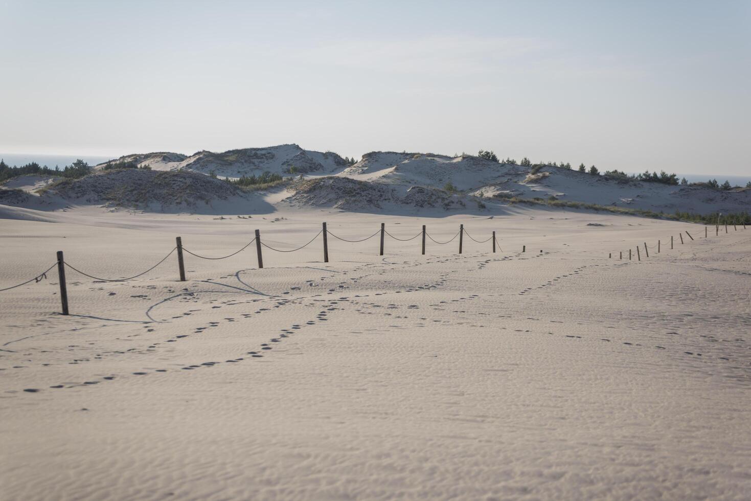 A fence with a wooden post in the sand photo