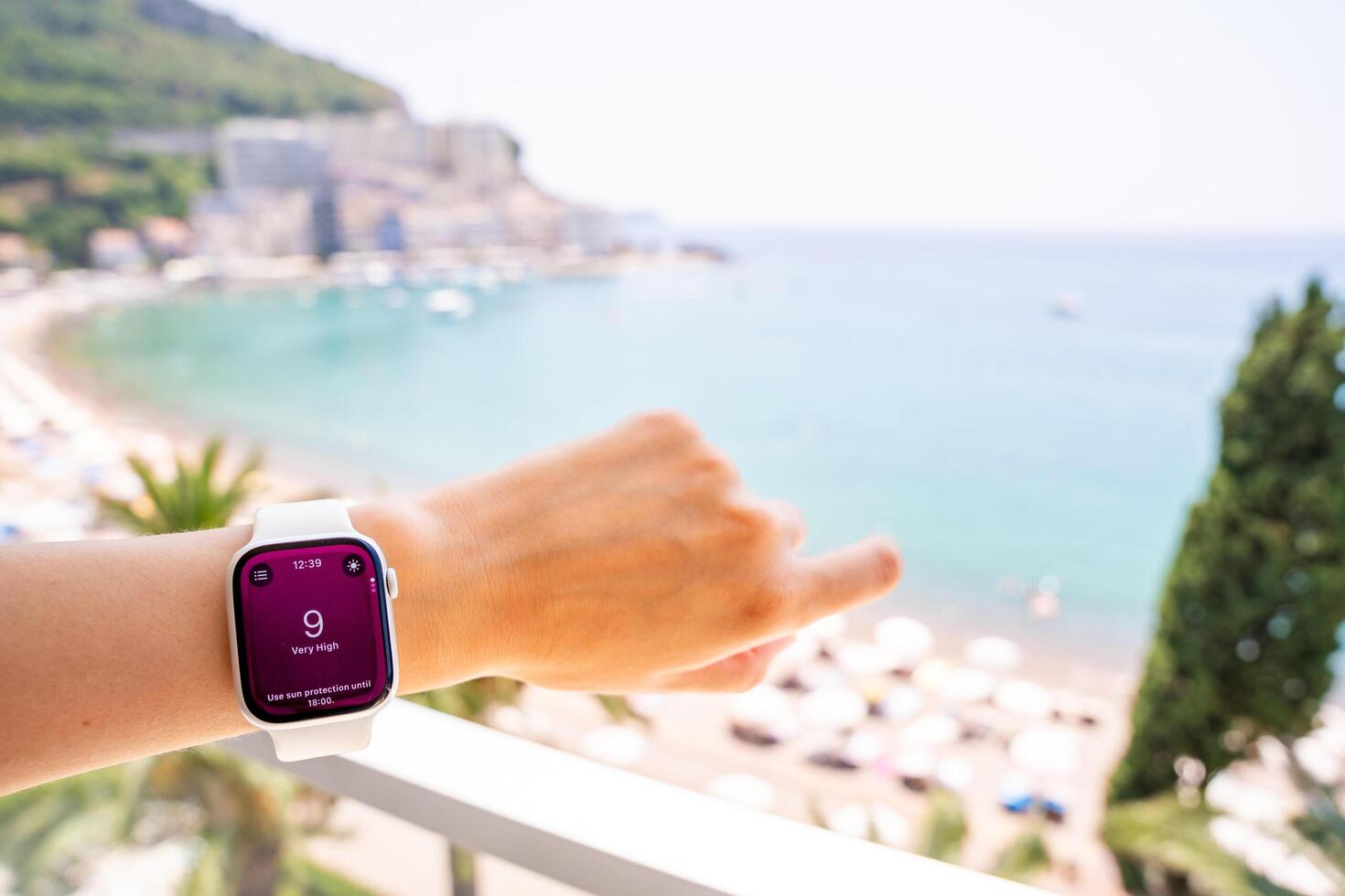 Budva, Montenegro - June 12, 2025. Smartwatch on wrist shows high UV index with beach, sea, and sun in background. Wearable technology helps track ultraviolet exposure during summer vacation. photo