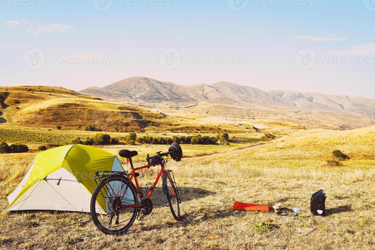 Panorama of unloaded touring red bicycle by green tent. Camping and bicycle touring concept Travel around Armenia by bicycle in mountains in autumn. photo