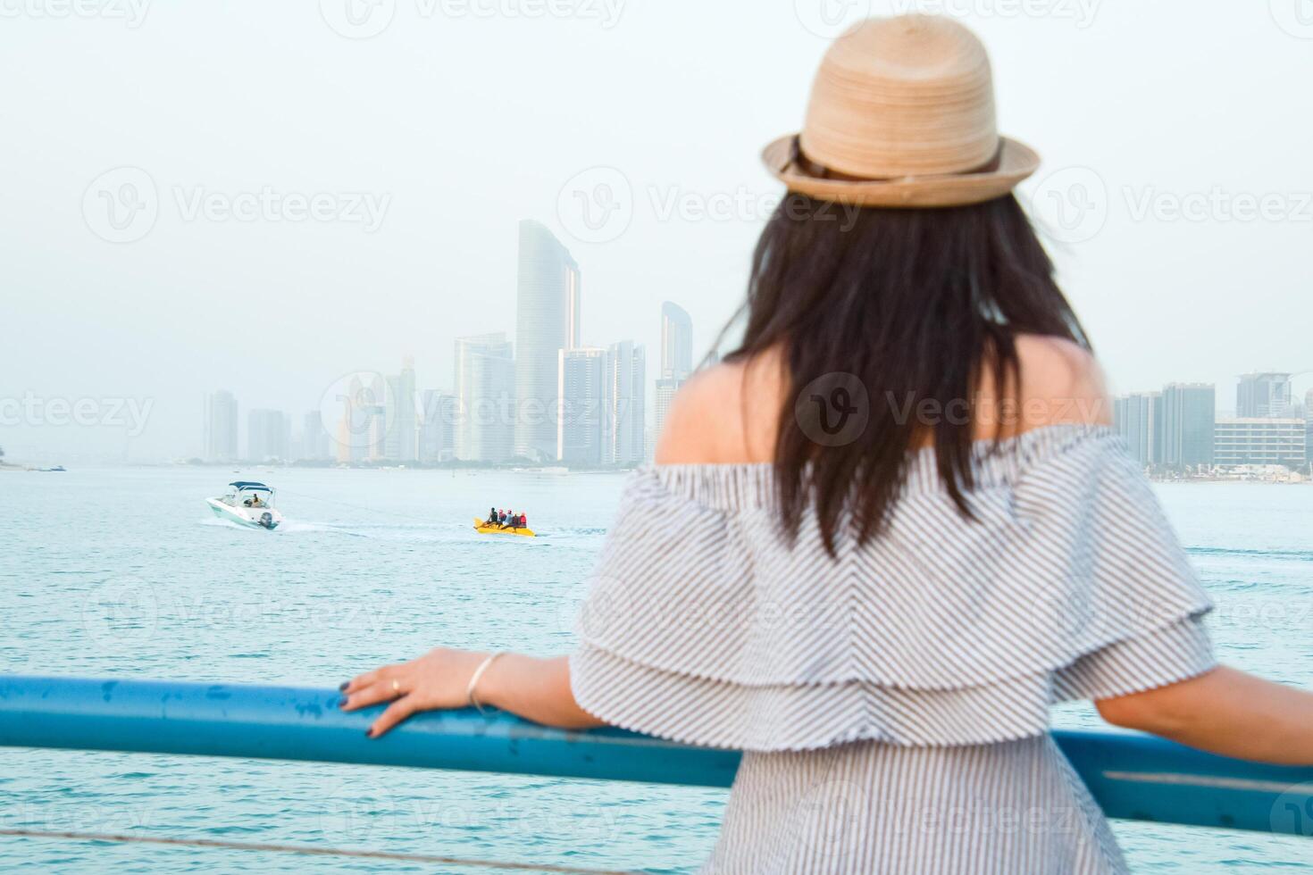 Against the stunning backdrop of Abu Dhabis skyline, a confident young woman dons a colorful turban, embodying the spirit of diversity and exclusivity that defines the UAE photo