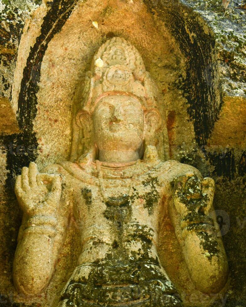 Ancient Bodhisattva statue carved in rock at Kushtarajagala site in Weligama Sri Lanka spiritual heritage site with stone sculpture and sacred hand gesture photo