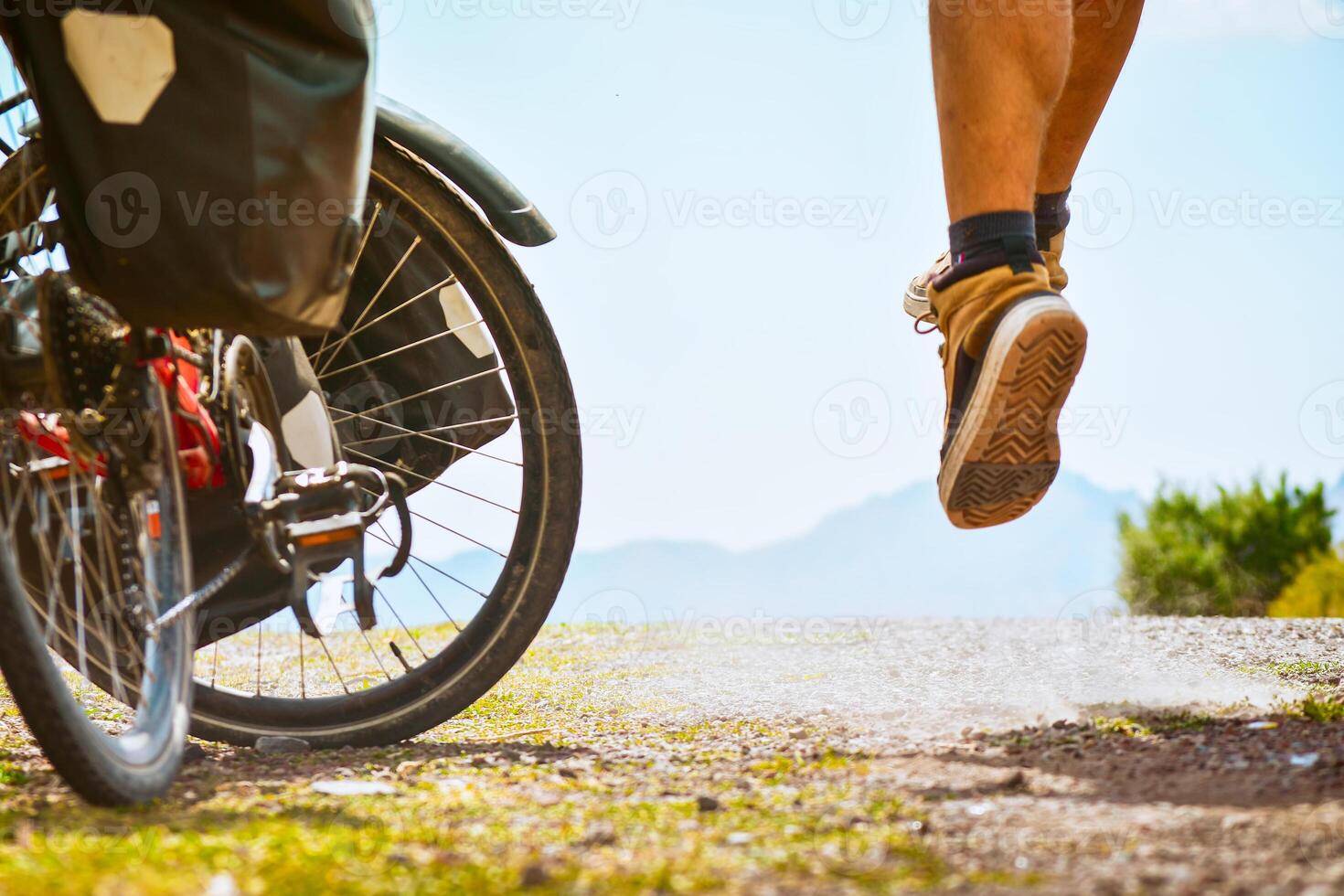 Cyclist on side of road jump in air posing for action camera and by his bicycle. Creative inspirational travel action photo. Inspirational mock up extreme sports photography. photo